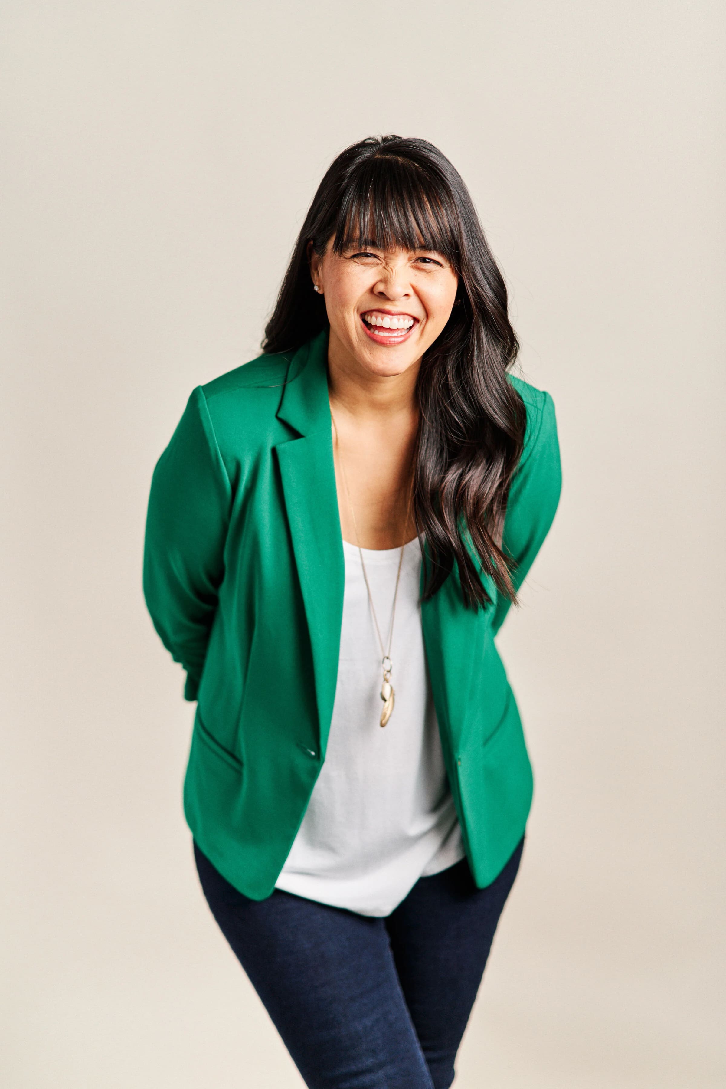 A woman in a green blazer laughing during a studio branding session.